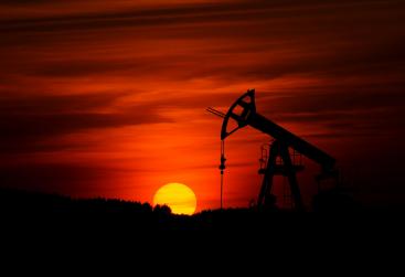 An oil pumpjack silhouetted against a red sunset